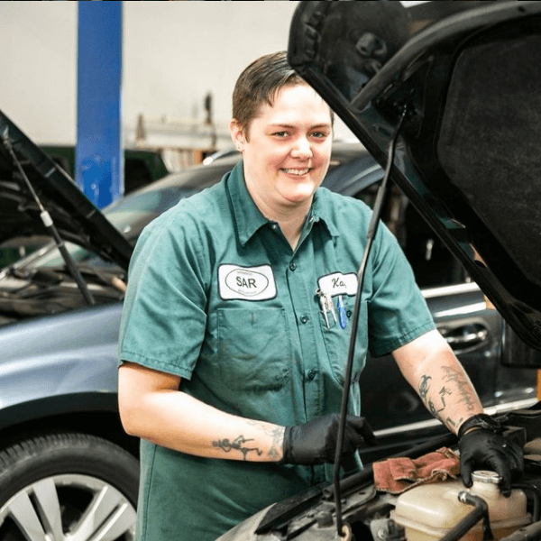 Katie smiling while working under a car hood